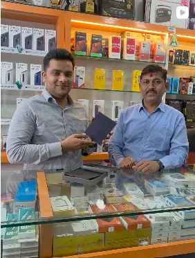 Matoshree Electronics owner with a customer holding a new mobile phone in the store